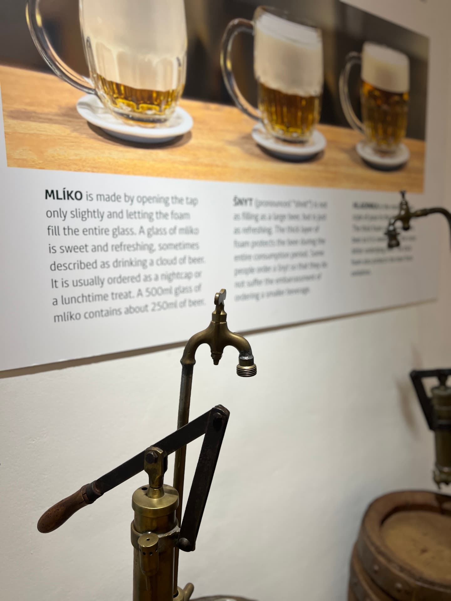 Exhibit on Czech beer pours (mlíko and šnyt) with a historic tap